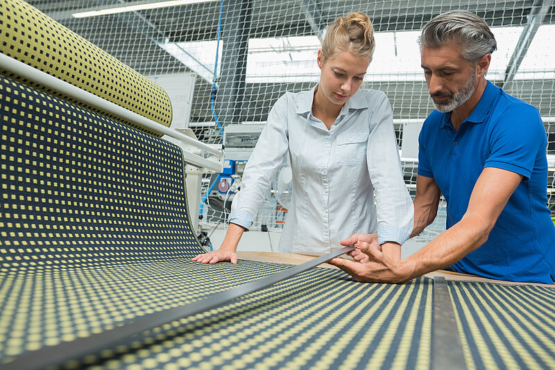 Frau und Mann in Fabrik bei Teppichherstellung