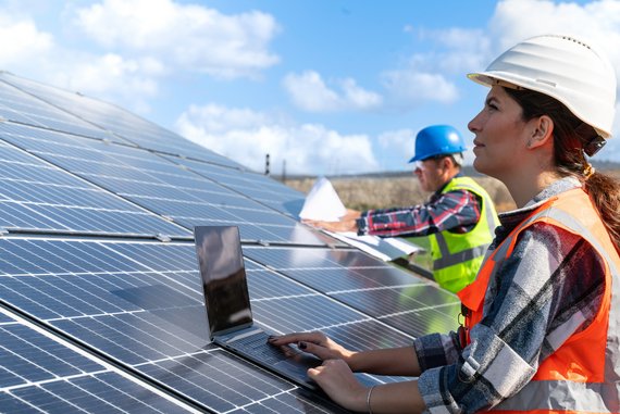 Bauarbeiterin auf Dach mit Photovoltaik