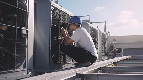 Arbeiter auf Gebäudedach arbeitet an einem Element zur Kühlung